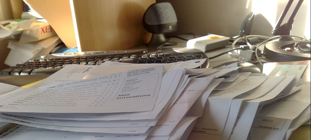 Mesa coberta por uma pilha bagunçada de papéis e documentos